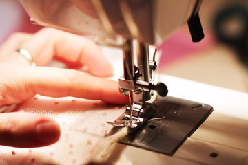 The woman works on the sewing machine. Clothes manufacture.