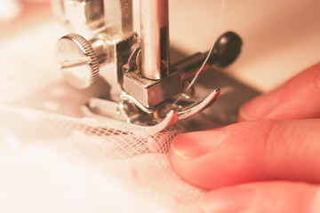 The woman works on the sewing machine. Clothes manufacture.