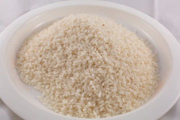 Fototapeta na wymiar Uncooked rice in a bowl on a white background.