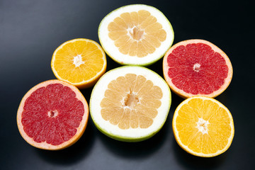 Naklejka na ściany i meble cut pieces of different citrus fruits on dark background
