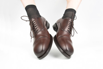 Male legs in socks and brown classic shoes on a white background