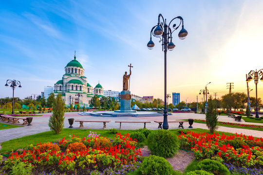 Beautiful colorful square in front of the Christian church in the city center during sunset with blue yellow sky. Monument to Saint Vladimir the Baptist and Vladimir Cathedral, Astrakhan, Russia.