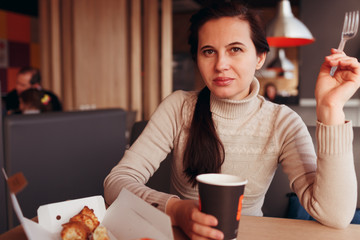 The woman has a rest in cafe. Sits at a table, eats and has tea