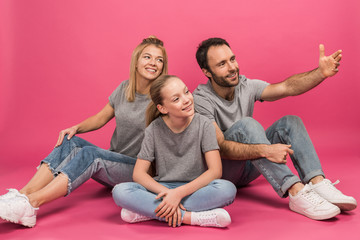 happy family with daughter sitting on pink while father showing something