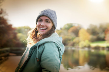 Happy attractive brunette smiling at camera outdoor in fall