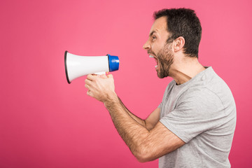 aggressive man shouting with megaphone, isolated on pink