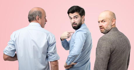 Are you talking about me concept. Horizontal portrait of three man, having doubtful confused uncertain facial expression