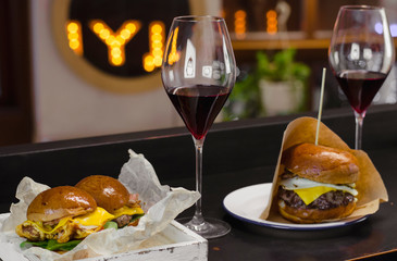 two glasses of wine and american burgers with chicken, beef and cheese in the restaurant