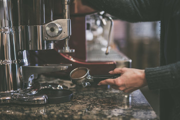 Im Cafe Hand hält Siebträger mit gemahlenem Kaffee an der Kaffeemaschine
