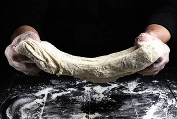 cook stretches kneaded dough from white wheat flour