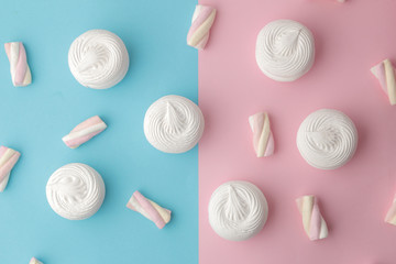 Background of sweet white marshmallows and small marshmallows on a bright trendy pink and blue background. Sweets. dessert. view from above