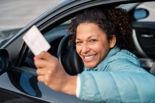 Black car driver woman smiling showing driving license