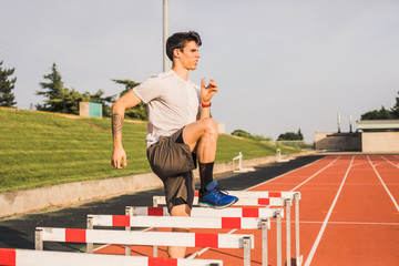 Athlete doing warm-up exercises on a tartan track for a hurdle race