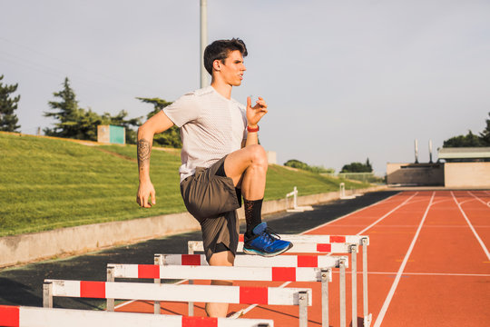 Athlete doing warm-up exercises on a tartan track for a hurdle race