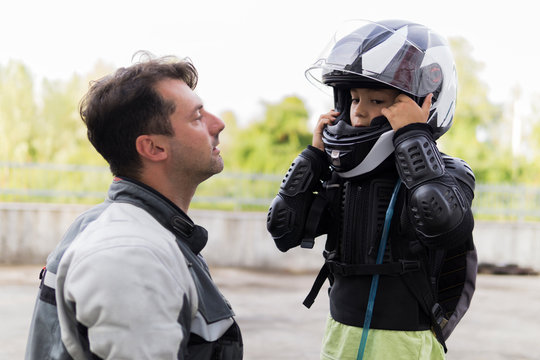 Father watching son putting on motorcycle helmet