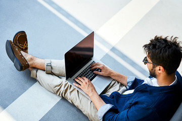 Young man sitting on the ground using laptop