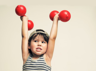 Fototapeta na wymiar The child is engaged in physical culture with dumbbells
