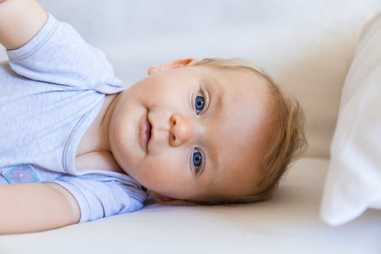 Portrait of blond baby girl lying on couch