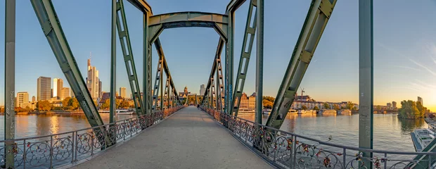eiserner Steg, berühmte eiserne Fußgängerbrücke überquert den Main in Frankfurt mit Skyline im Morgenlicht © travelview