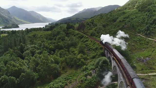 Beautiful drone flight tracking the Jacobite steam train near the famous Glenfinnan viaduct in Scotland