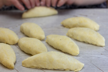 raw pies on the table against the background of female hands making pies