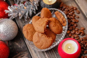 Cookies filled with chocolate, Christmas balls, candles and coffee beans. Close-up on the old rustic wooden table