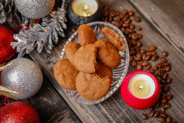 Cookies filled with chocolate, Christmas balls, candles and coffee beans. Close-up on the old rustic wooden table