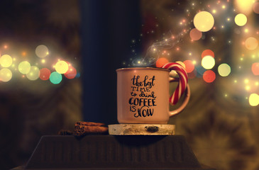 a cup of coffee with Lollipop standing on the stove against holiday lights background
