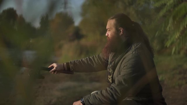 Bearded fisherman fishing with fishing pole. Fisher focuses on fishing.