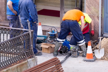 plumbers in construction site repairing water pipe line in city street , motion blur