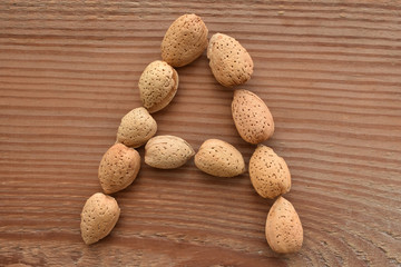 the letter A shaped with almonds on wood