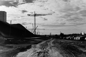 View of the construction site with cranes and high-rise residential buildings. Black and white photo