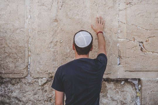 Man hand and pray paper on the Western Wall, Wailing Wall the Place of Weeping is an ancient limestone wall in the Old City of Jerusalem. Second Jewish Temple by Herod the Great