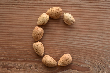 the letter C shaped with almonds on wood