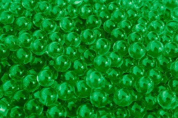 Water green gel balls with bokeh. Polymer gel. Silica gel. Balls of green hydrogel. Crystal liquid ball with reflection. Green texture background. Macro