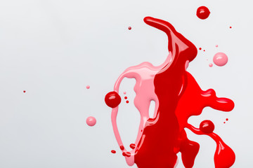 top view of bright abstract multicolored spills of nail polish isolated on grey