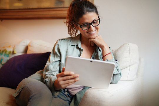 Casual attractive woman on couch at home with tablet