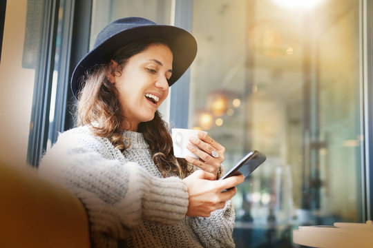 Cool attractive woman in modern cafe with cellphone