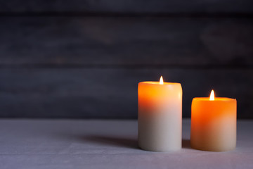 Close up of Two thick candles lit front view with rustic wood background