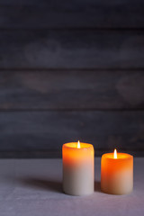 Fototapeta na wymiar Close-up of Two lighted candles lit front view with rustic and vertical wood background