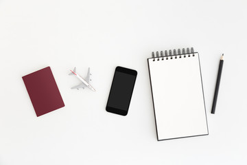 Passport, mobile, notepad, plane on office desk. Flat lay.