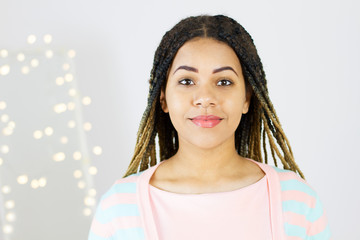 comely pretty smiling girl with dreadlocks on home blurred bokeh background