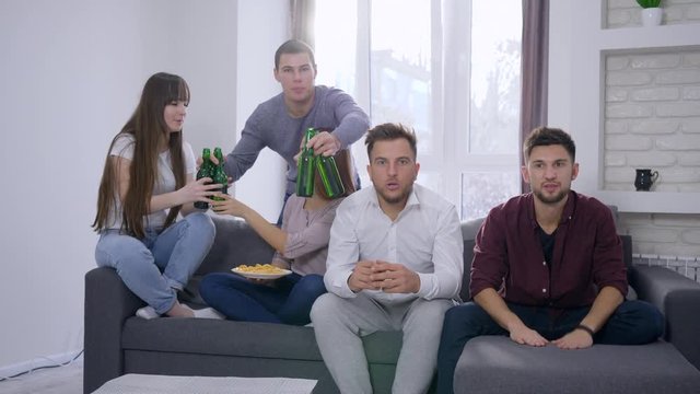 nervous fans attractive young people are watching match on TV, friends brings beer and pizza for celebrating success at home party