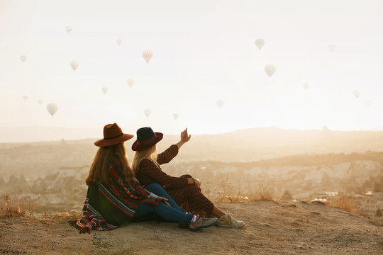 Travel. Women Looking At Flying Hot Air Balloons In Sky