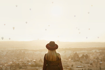 Travel. Beautiful Woman In Hat With Flying Air Balloons In Sky