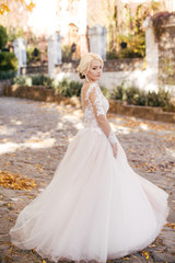 Fototapeta na wymiar Beautiful blonde bride in white dress in the garden
