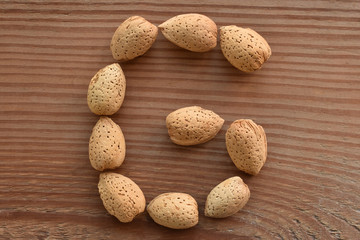 the letter G shaped with almonds on wood