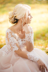 Fototapeta na wymiar Beautiful blonde bride in white dress in the garden