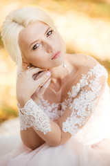 Beautiful blonde bride in white dress in the garden