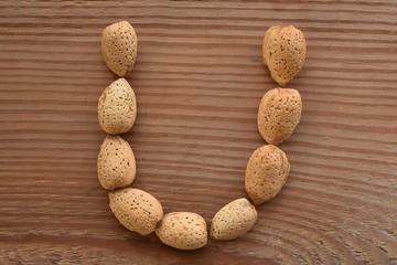 the letter U shaped with almonds on wood